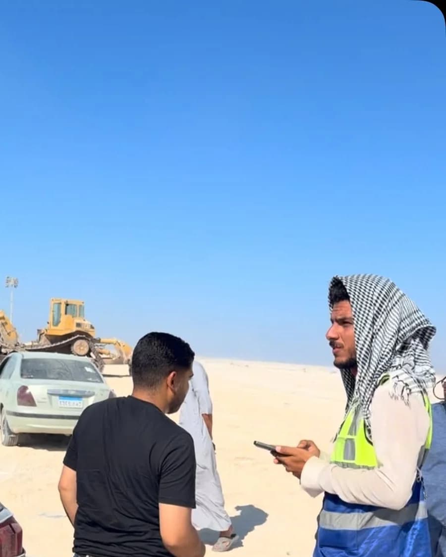 فريق مساحة ميداني من كيان في موقع إنشاءات صحراوي ومعدات الحفر في الخلفية