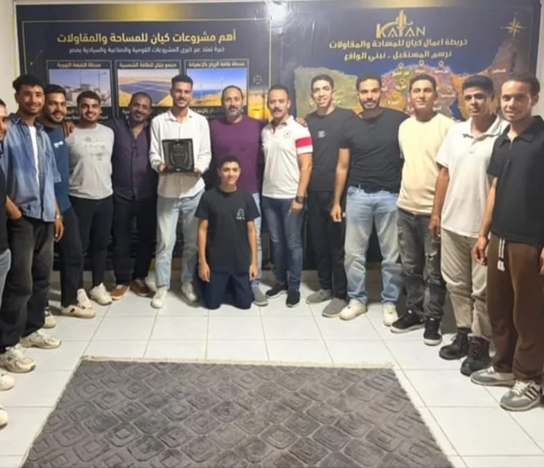 فريق كيان للمساحة والمقاولات أمام لوحة خريطة أعمال الشركة بمقرها